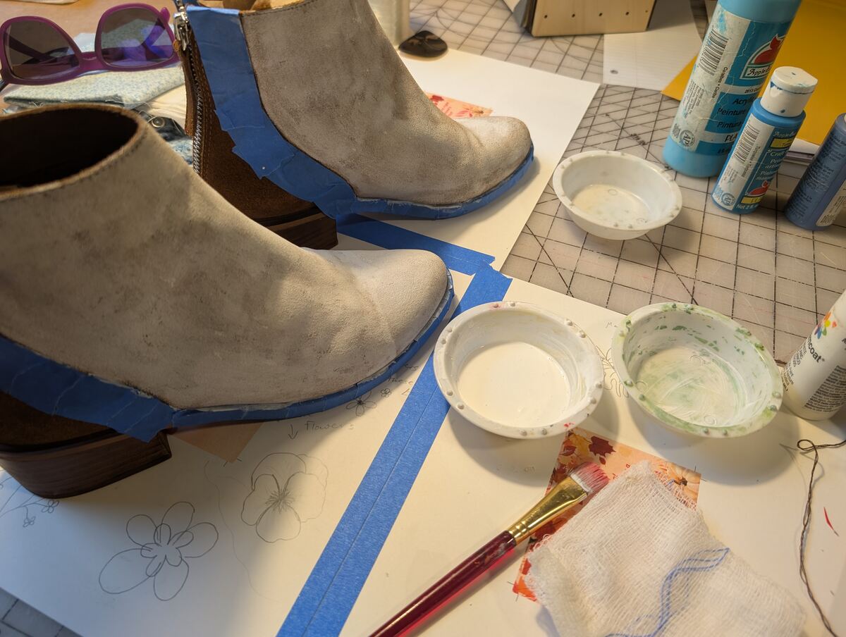 Two brown boots being painted white