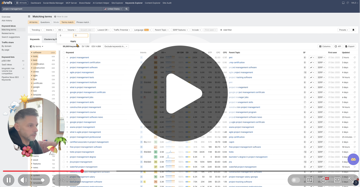 Screenshot of Ahrefs Keywords Explorer filtered to low keyword difficulty for “project management,” showing matching terms with search volume, KD, CPC, and intent data, overlaid with a large play button and a small circular video of a man speaking in the bottom left.