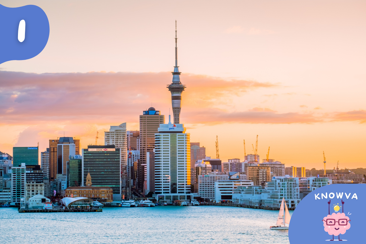 Auckland skyline at sunset with the Sky Tower rising above the harbour and city buildings.